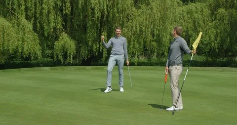 Two Brothers playing golf, one sinks the putt and celebrates! Vídeos de archivo 101644129
