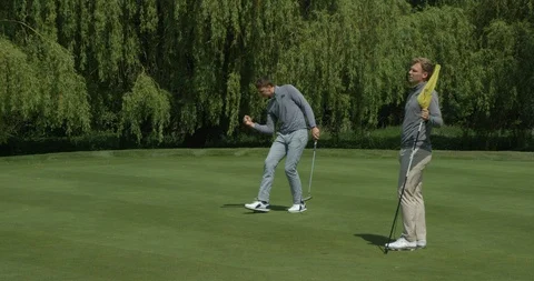 Two brothers playing golf as one sinks a putt. Video stock 101644999