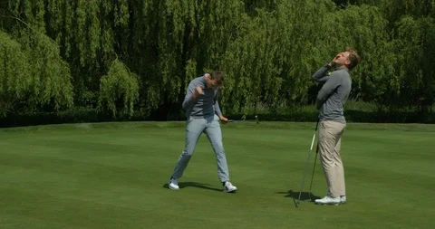 Two brothers playing golf, one sinks the putt and celebrates! Vídeo Stock 101645499