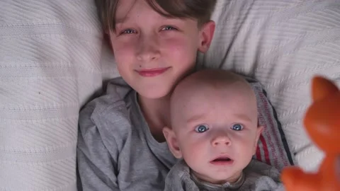 Two brothers , small and large, older and younger lie playing and having fun Stock Footage 235773200