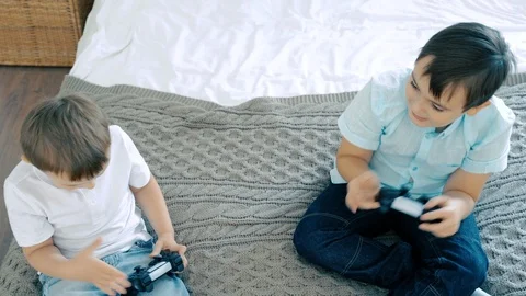 Two brothers smiling and having fun playing a video game with controllers Stock Footage 118614811