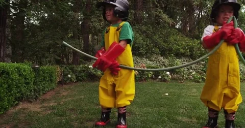 Two brothers work together to control the water pressure of their garden hose. Stock Footage 69185964