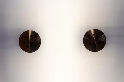 Two brown circular metal objects placed symmetrically on a white surface Stock Photos