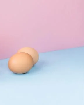 Two brown eggs on a light blue and pink background Stock Photos