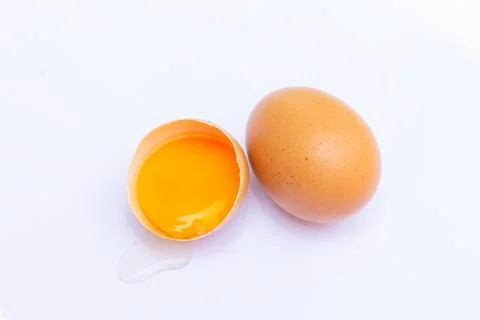 Two brown eggs With one egg broken in half, with a yolk inside the eggshell,  Stock Photos