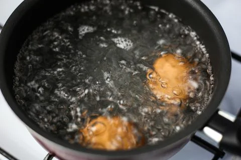 Two brown eggs in a pot of boiling water Stock Photos