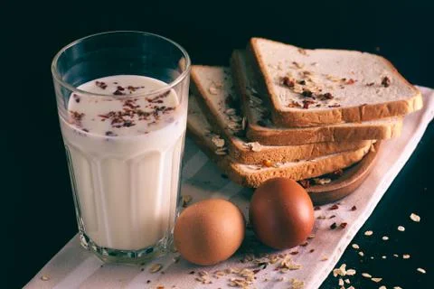 Two brown eggs,  white bread and a glass of milk on a linen tablecloth. Stock Photos