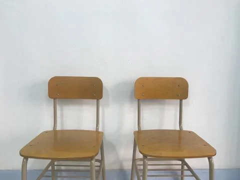 Two brown empty school chairs with white wall Stock Photos