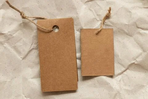 Two brown empty tags lie on brown crumpled paper as a mockup Stock Photos