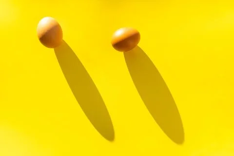 Two brown farm eggs on a yellow background in bright light, a concept of Stock Photos