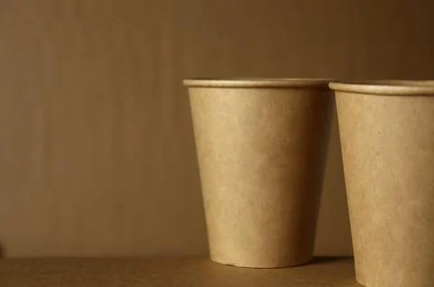 Two brown paper cups placed on a wooden surface in a simple setting with a Foto stock