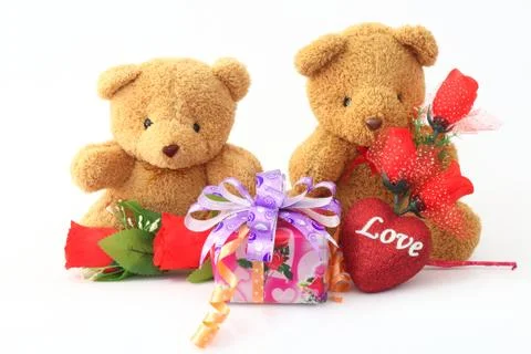 Two brown teddy bear holding a rose and a gift box on a white background. Stock-Fotos