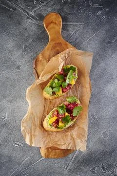 Two Bruschettas with Avocado paste, Tuna, Orange and cilantro on wooden cut.. Stock Photos