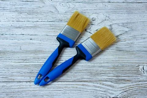 Two brushes with blue handles on a painted white wooden background. Stock Photos