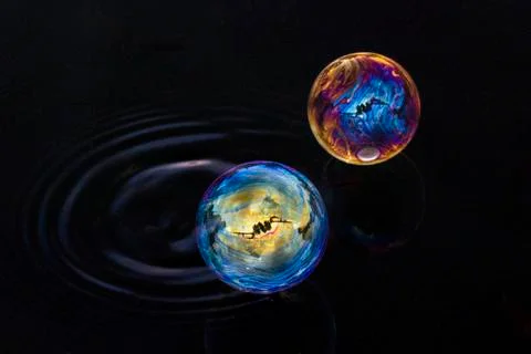 Two bubbles of different colors floating over the water Stock Photos