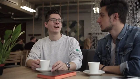 Two buddies sitting in the cafe and chatting with each other Stock Footage 74855402