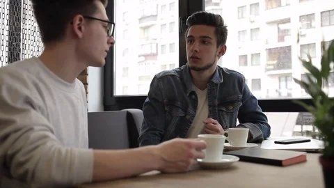 Two buddies sitting in the cafe and chatting with each other Stock Footage 74855420