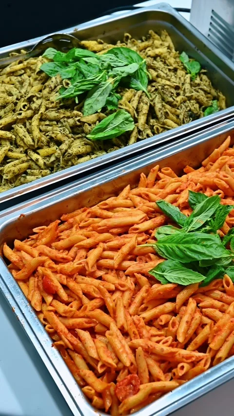 Two buffet trays with pesto and tomato penne pasta. Top view of stainless steel Stock Footage 329511280