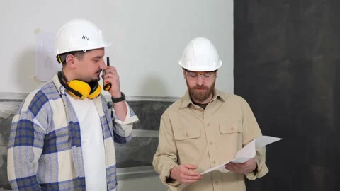 Two builder engineer are holding an apartment plan in their hands and discussing Stock Footage 236507454