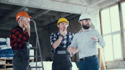 Two builders and a foreman discussing a plan for upcoming work at a construction Video stock 130776525