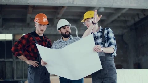 Two builders and a foreman engineer discussing a plan for upcoming work at a Stock Footage 130776620