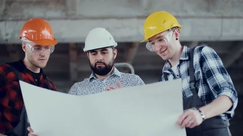 Two builders and foreman engineer are studying the work plan at the construction Stock Footage 131692496