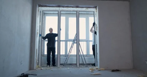 Two builders are dismantling plastic window, dismantling doorway from plastic Stock Footage 129838645