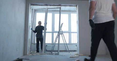 Two builders are dismantling plastic window, dismantling doorway from plastic Stock Footage 129838735