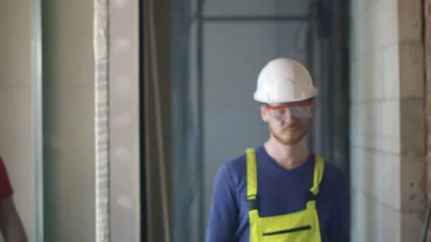 Two builders with arms crossed looking at camera on construction site background Video stock 133637730