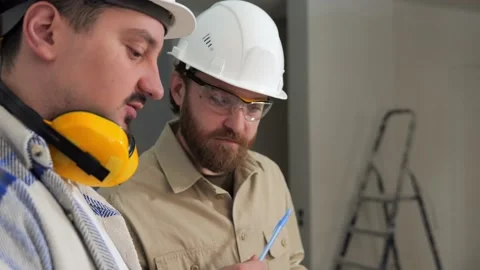 Two builders on a construction site discussing the layout of the room Stock Footage 236055027