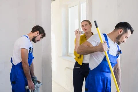 Two builders cover the wall with a roller Stock Photos
