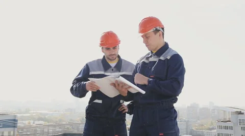 Two builders discussing the plan of the building Stock Footage 68422792