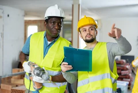 Two builders discussing working plan in apartment during repair works Stock Photos