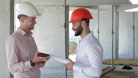 Two builders engaged in a lively discussion over a digital tablet at a Stock Footage 311649753