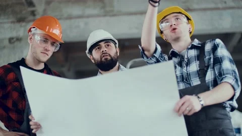Two builders in helmets and overalls at a construction site are discussing a Stock Footage 130776697