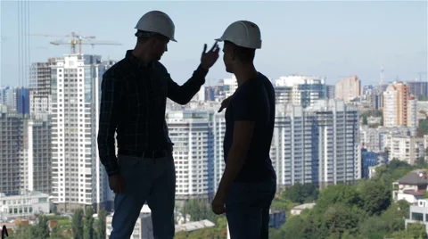 Two builders look at the landscape of high buildings Stock Footage