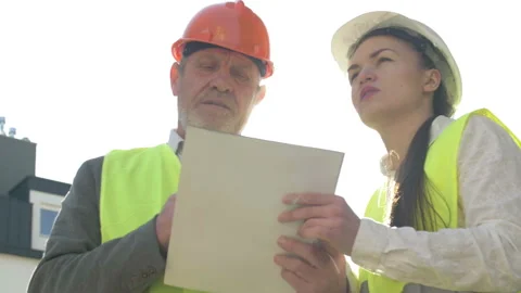 Two builders, a man and a young woman, are discussing something at the Stock Footage 127114110