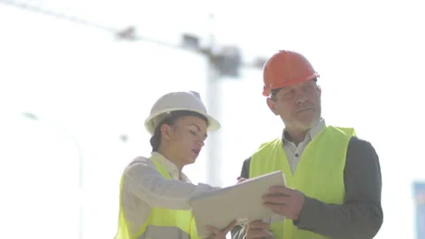 Two builders, a man and a young woman, are discussing work issues. Against the Stock Footage 127157959