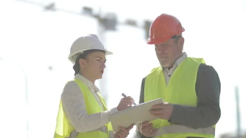 Two builders, a man and a young woman, are discussing work issues. Against the Stock Footage 134177381