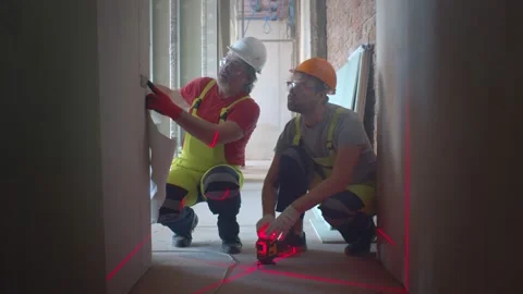 Two builders measuring wall level with construction laser level Stock Footage 133638578
