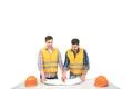 The two builders with a paper on a table discuss on the white background Photo