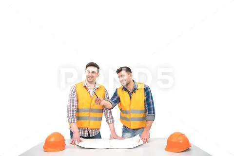 The two builders with a paper on a table discuss on the white background Stock Photos