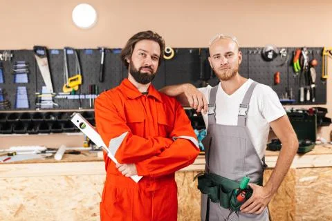 Two builders in work clothes thoughtfully looking in camera spen Stock-Fotos