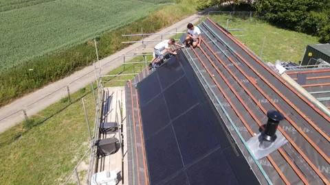 Two builders working on a solar panel on the roof of a new build Video stock 246384170