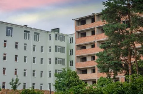 Two buildings on the construction site. A green structure and an unfinished r Stock Photos