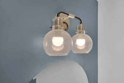 Two-bulb vanity light fixture with speckled glass globes on a blue wall. 库存照片