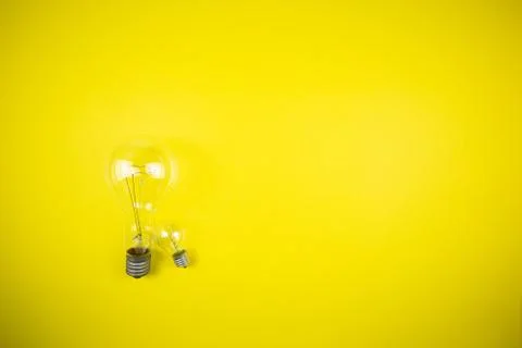 Two bulbs - large and small. Yellow background Foto stock