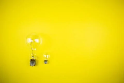 Two bulbs - large and small. Yellow background Foto stock