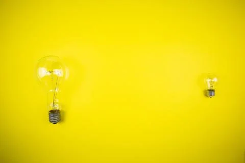 Two bulbs - large and small. Yellow background Stock Photos