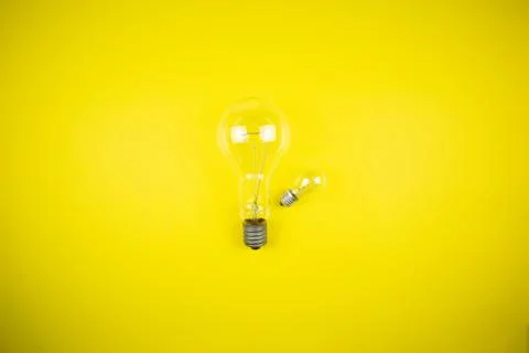 Two bulbs - large and small. Yellow background Stock Photos